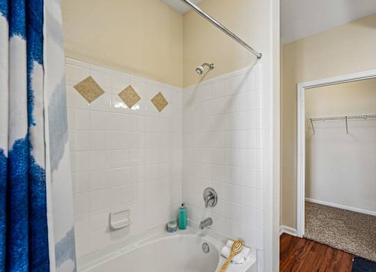 A bathroom with a white tub and a blue shower curtain.