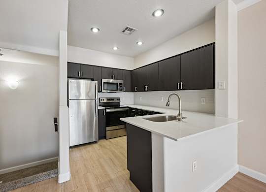 A kitchen with a white fridge and black cabinets.