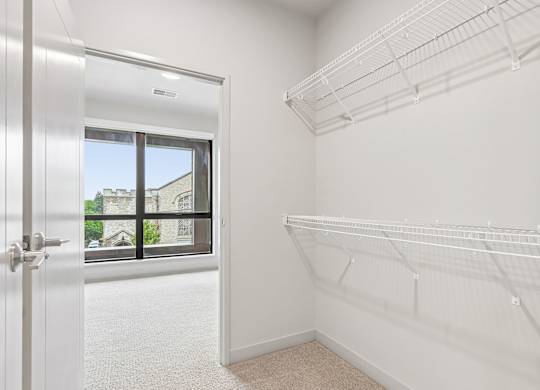 A white closet with shelves and a door leading to a balcony.