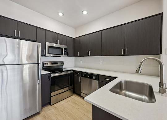 A kitchen with a stainless steel refrigerator, microwave, oven, dishwasher, and sink.