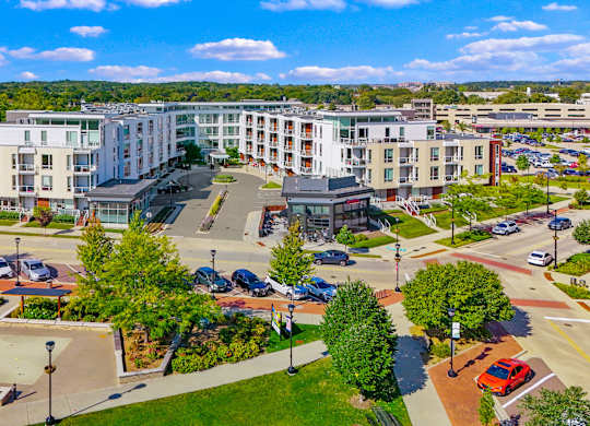 A view of a city with apartment buildings, trees, and a parking lot.