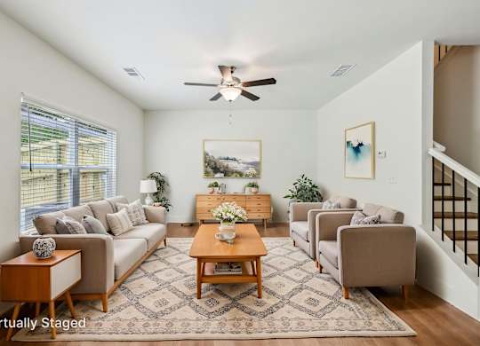 A living room with a couch, chairs, and a rug.