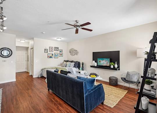 A living room with a blue couch and a ceiling fan.