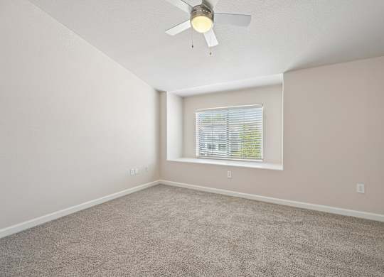 A room with a ceiling fan and a window with blinds.