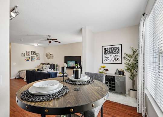 A dining room with a table set for two and a television in the corner.