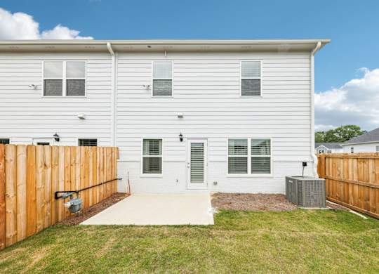 A white house with a grey door and windows with a wooden fence.