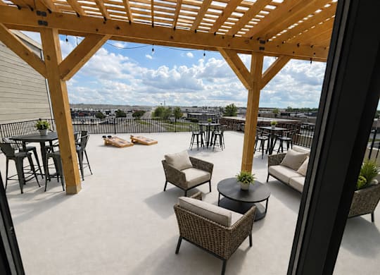 Kokomo, IN, Apartments with In-Unit Washer and Dryer - The Elwood Apartments - Rooftop Lounge With A Wooden Pergola, Lounge Seating, High Top Tables, Cornhole Boards, And Open Sky Views.