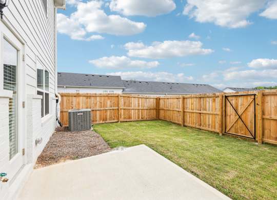 A backyard with a wooden fence and a concrete patio.