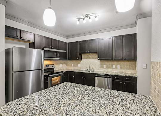 A kitchen with black cabinets and a stainless steel refrigerator.