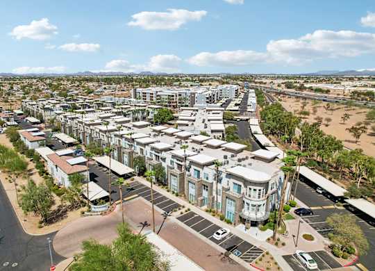 A large, modern residential complex with a parking lot in front.