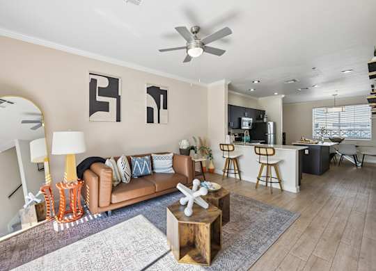 A living room with a brown couch, a wooden coffee table, and a ceiling fan.