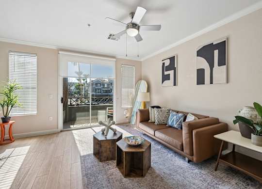 A living room with a brown couch, a coffee table, and a ceiling fan.
