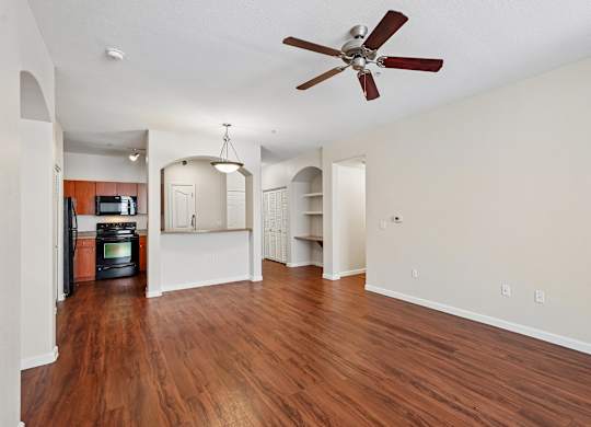 A room with a ceiling fan and wooden floors.