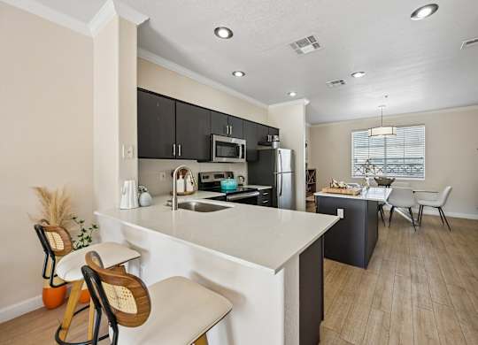A kitchen with a white countertop and black cabinets.