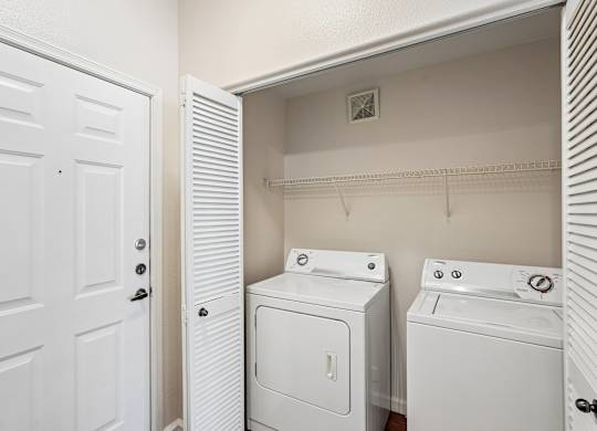 A white door is open to a laundry room with a washer and dryer.