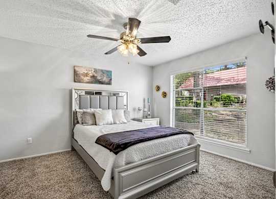 A bedroom with a large bed and a ceiling fan.