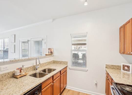 A kitchen with a sink, stove, and cabinets.