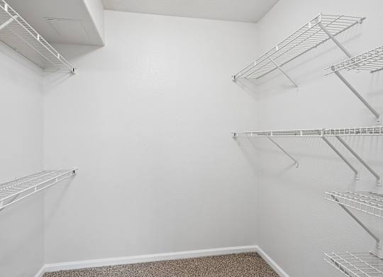Empty walk-in closet with white shelving.