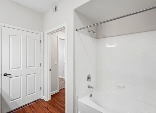 A white bathroom with a tub and a door.