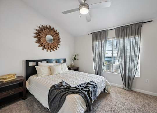 A bedroom with a bed, a ceiling fan, and a mirror on the wall.