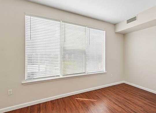 A room with a window covered by white blinds.