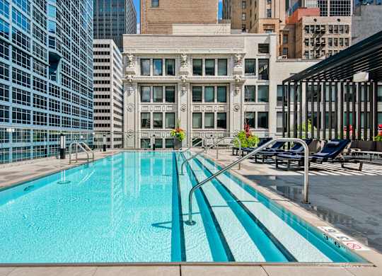 A swimming pool with a blue tinted water in the middle of a city.