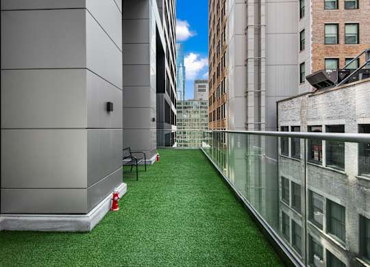 A long, narrow, glass-walled atrium with a green carpet and a red fire extinguisher.