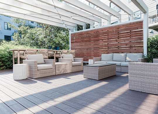 A patio with white furniture and a wooden wall.