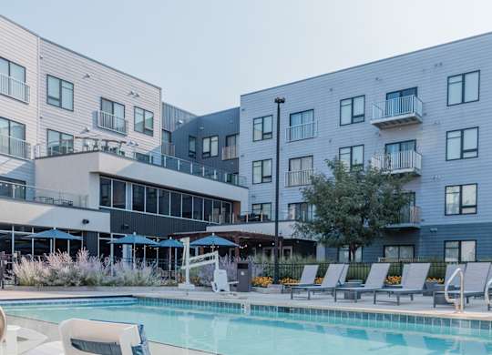 A pool area with a white chair and a white table in the foreground.