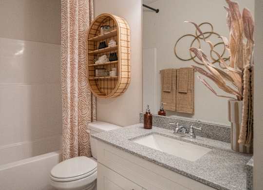 A bathroom with a toilet, sink, and a decorative tree.