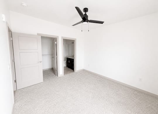 A room with a ceiling fan and carpeted floor.