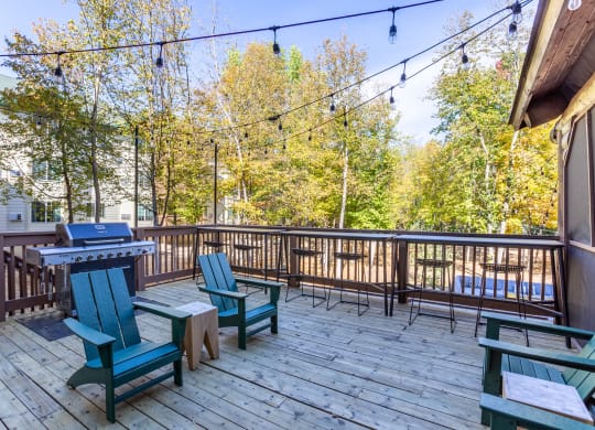 a deck with a picnic table and chairs and a grill at Birchwood Apartment Homes in Maple Grove, MN