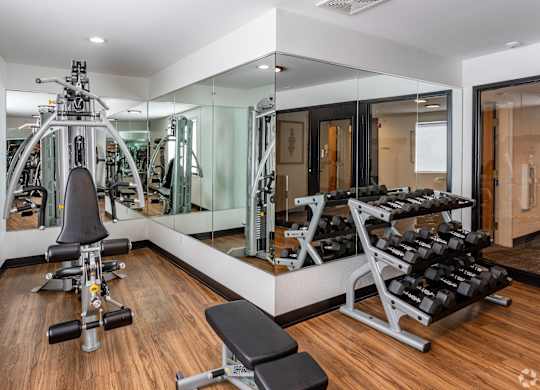 a gym with weights and mirrors and a wood floor
