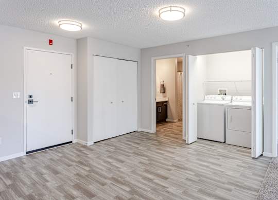 a white kitchen and laundry room with a wood floor and white doors