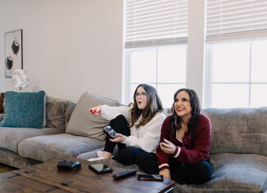 two women sitting on a couch playing a video game