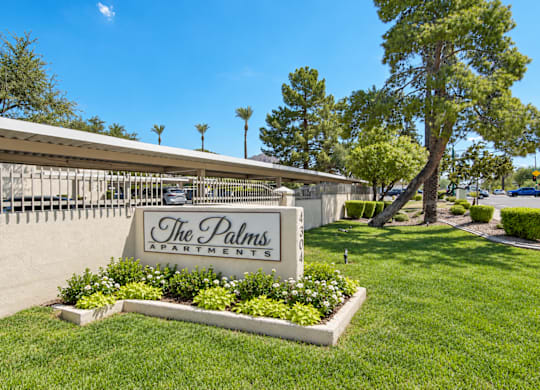 The Palms Apartments sign is in front of a building.