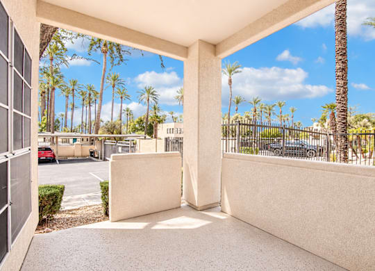 A view from a patio looking out to a parking lot and palm trees.