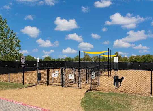 A dog park with a yellow canopy and a black fence.