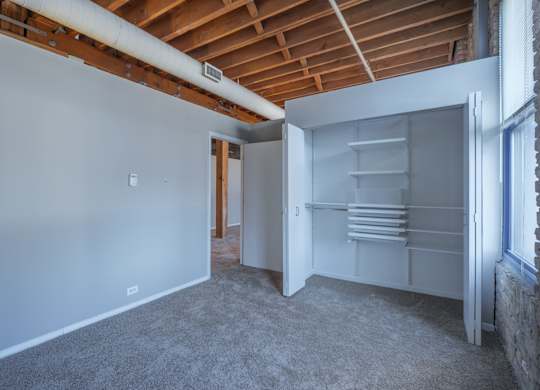 A room with a white wall and a white closet with shelves.