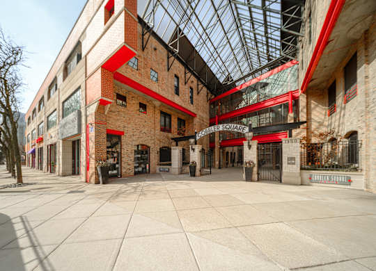 A large open plaza with a glass ceiling and brick buildings on either side.