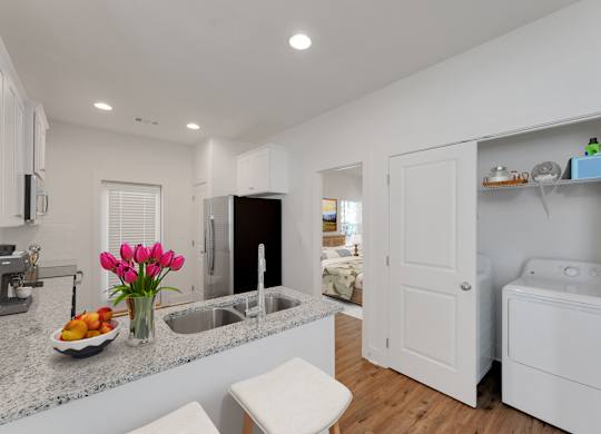 A kitchen with a white counter top and a bowl of fruit on it.
