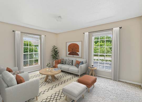 A living room with a grey couch, a brown ottoman, a wooden coffee table, and a potted plant.