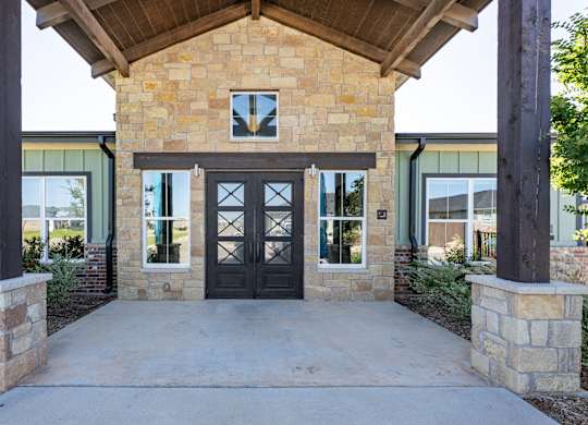 A building with a black door and windows is surrounded by pillars.