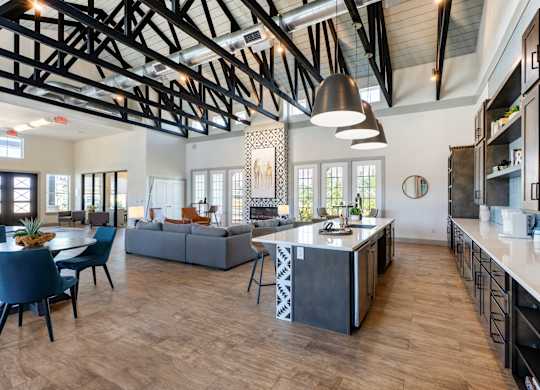 A modern kitchen with a large island and a dining table with chairs.