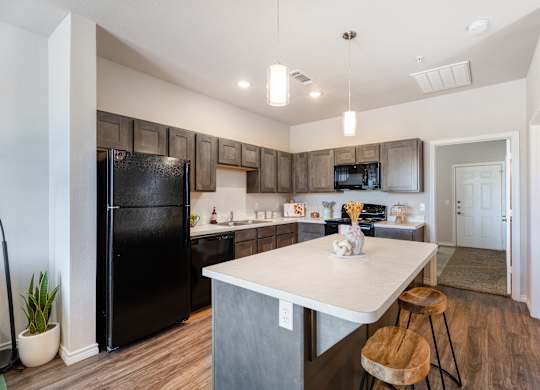A kitchen with a black fridge and wooden cabinets.
