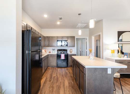 A modern kitchen with a black refrigerator and wooden floors.