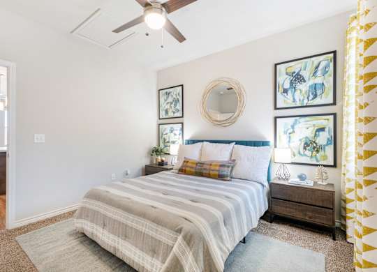 A bedroom with a bed, nightstand, and a ceiling fan.