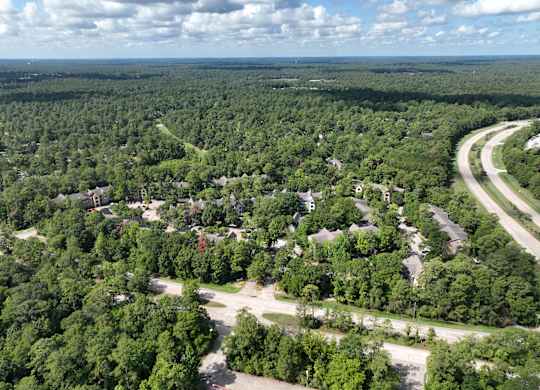 A bird's eye view of a residential area surrounded by a dense forest.