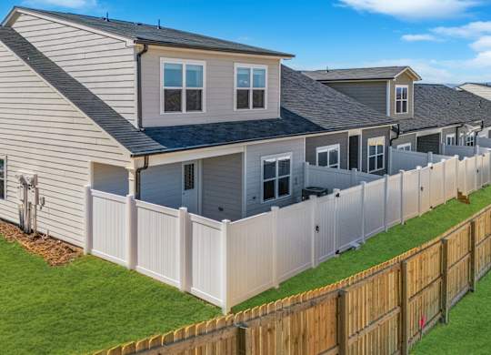 A house with a grey roof and a white fence.