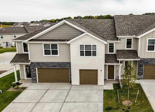 A large house with a grey roof and a brown garage door.